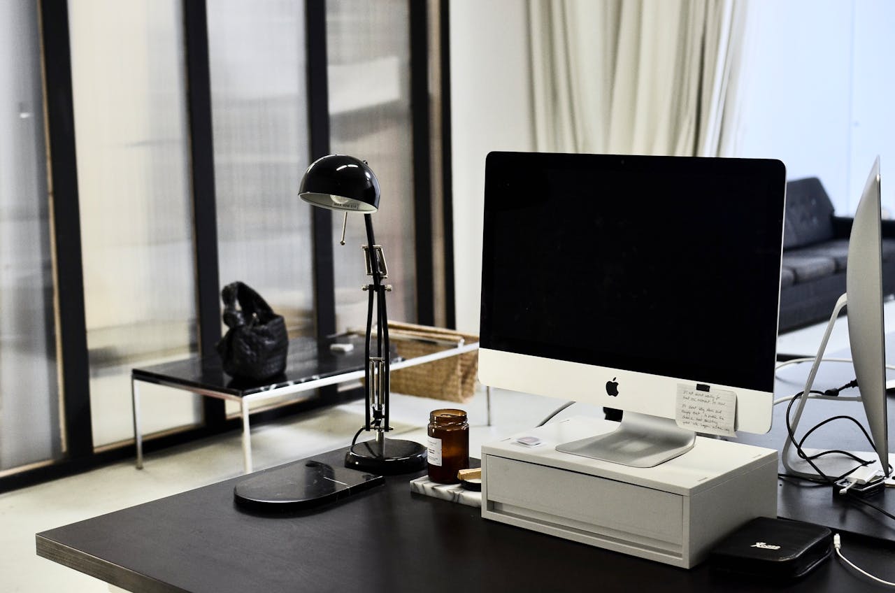 Sleek modern office with computer, lamp, and minimalist furniture.